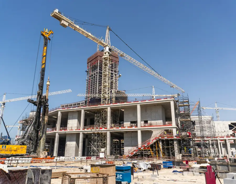 Concrete building rising beside a tower crane on a sunny day