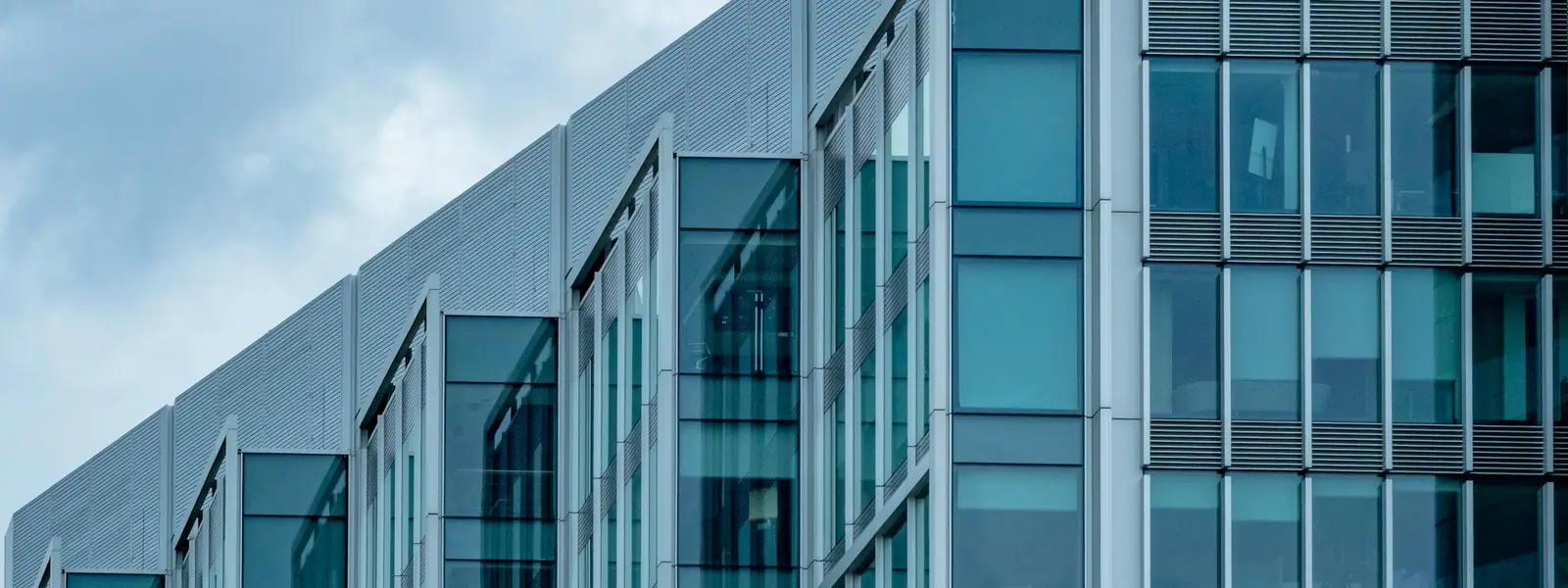 Modern glass office building against a clear blue sky