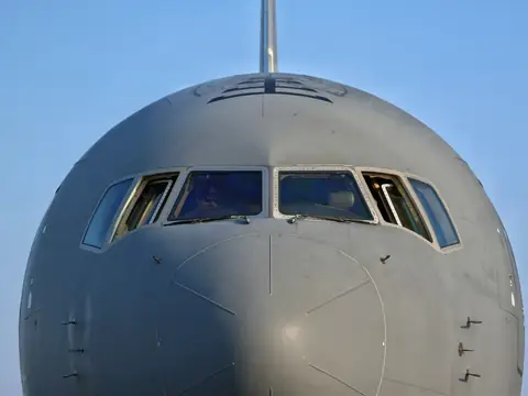 Nose and cockpit of a grey military tanker aircraft against a blue sky